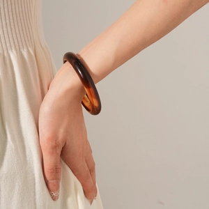 Close-up of translucent amber resin bangle showing smooth texture on woman wrist