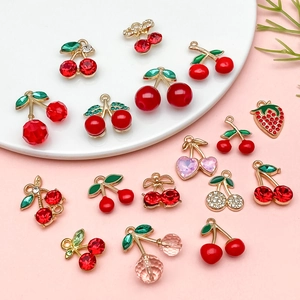 Close-up of red cherry and strawberry alloy pendants with sparkling crystal details