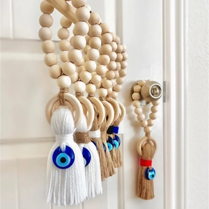 Detail of wooden bead tassel with evil eye charm hanging on a solid wood door