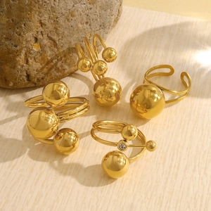 Detailed view of gold ball rings with multi-layer bands and zircon on natural stone