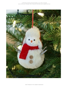 Close-up of a plush snowman ornament hanging on a Christmas tree with warm lights
