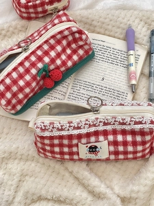 Knitted cherry plaid pencil case and lace checkered makeup bag on beige plush rug