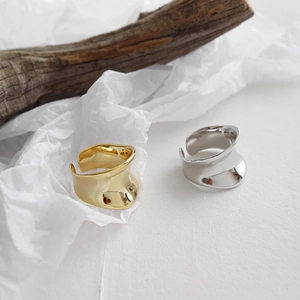 Minimalistische goldene und silberne konkave Ringe auf Holz und Papier im modernen Design