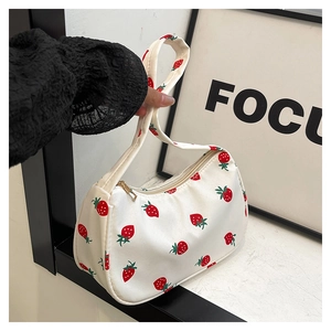 Detail of red strawberry print on white canvas bag with premium gold zipper