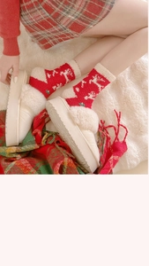 Detailed view of warm Christmas socks with fleece slippers on a soft winter rug