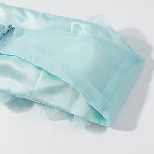 Détail du tissu en satin bleu clair avec fermeture éclair assortie et bord en maille plissée