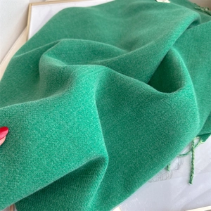 Close-up of green cashmere-feel scarf fabric texture with detailed fringe tassels