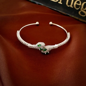Exaggerated silver snake-shaped open bracelet with green zircons and white crystals