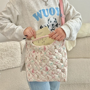 Detailed shot of quilted white crossbody bag with cute animal patterns and pink strap