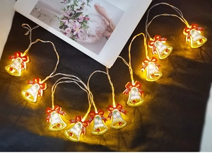 Detail of festive LED Christmas bell string light with red bow emitting warm yellow glow