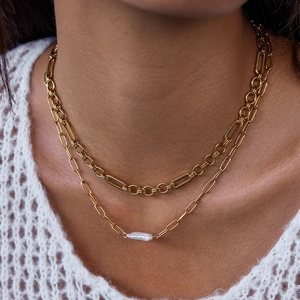 Dubbellaagse gouden paperclipketting met een barokke parelhanger op een model
