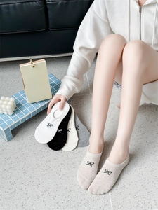 Close-up of low cut no-show socks featuring a small sweet bow tie and knitted texture