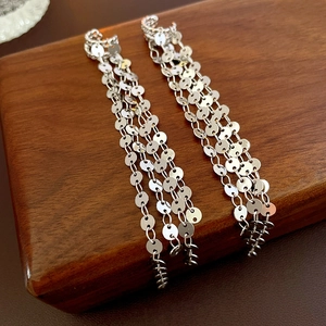 Chic silver sequin tassel clip-on earrings with layered metal chains on a luxury display