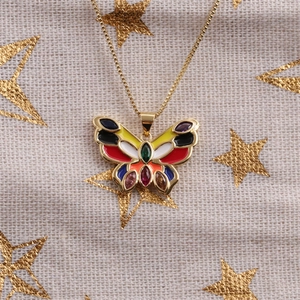 Détail d'un pendentif papillon doré avec émail coloré et petites pierres précieuses