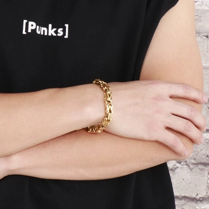 Close-up of a chunky golden stainless steel Byzantine chain bracelet on a male wrist