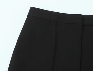 Detail of high waist black trousers featuring a concealed fly and precise sewing crafts
