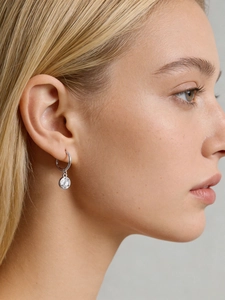 Macro detail of a 925 sterling silver hoop earring with a round sparkling zircon pendant