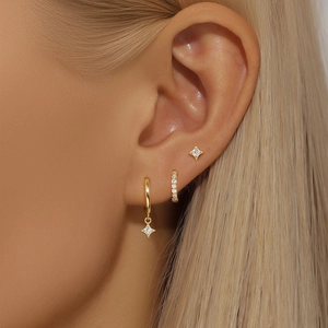 Macro shot of gold star pendant earrings with micro-set zircons on female ear