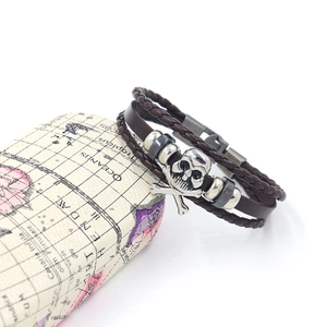 Detail of multi-layer leather bracelet with silver skull charm and metallic beads