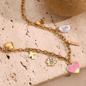 Macro detail of 18K gold plated necklace with pink heart and Amour charm on stone