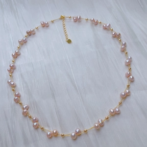 Detail of pink freshwater pearl necklace with gold beads on white silk background