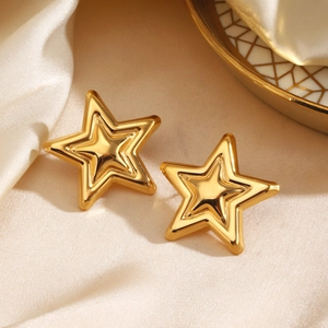 Elegant pair of 3D gold star stud earrings resting on premium beige silk fabric