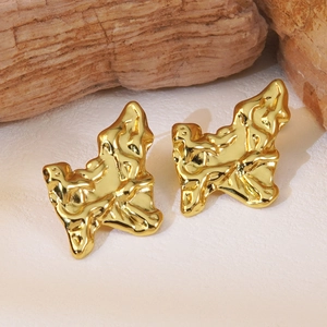 Detail of gold irregular hammered earrings with lava-like texture on natural rock