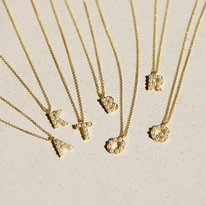 Close-up of elegant gold necklaces with personalized pearl alphabet letter pendants