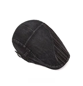Dettaglio della coppola in denim nero lavato con cuciture a contrasto bianche e fibbia in metallo