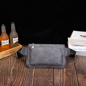 Matte dark grey cross-body chest bag with nylon strap on a vintage wood desk