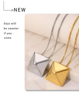 Macro shot of 18k gold and silver pyramid pendants on box chains hanging on a cup