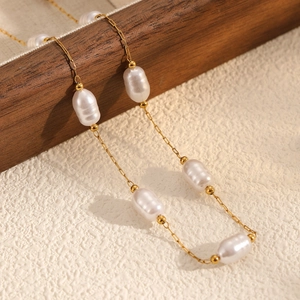 Baroque irregular pearl necklace with 18k gold plated chain on a textured wooden stand