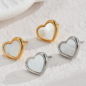 Macro view of gold and silver heart earrings with white mother of pearl inlay detail