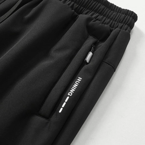 Detail der schwarzen Fleecehose mit elastischem Bund und Reißverschlusstasche mit Runing-Print