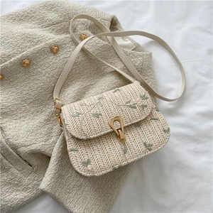 Détail du sac selle en paille tressée avec broderie florale et fermoir en métal doré en U