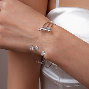 Gros plan sur un bracelet ouvert multicouche argenté avec zircons sur soie blanche