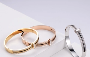 Close-up of titanium steel bangles in gold, rose gold and silver with zircon inlays