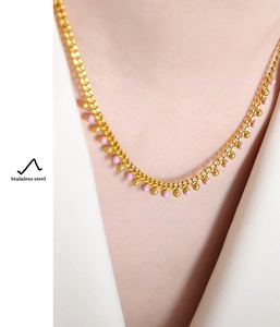 Detail of gold-plated stainless steel necklace with pink bead pendant on model