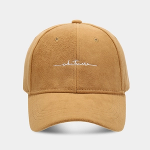 Detailed view of white 'whatever' script embroidery on a camel faux suede baseball cap