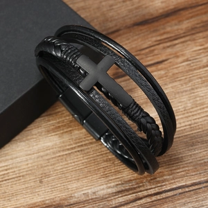 Detail of multi-layer black leather bracelet with metal cross on wooden surface