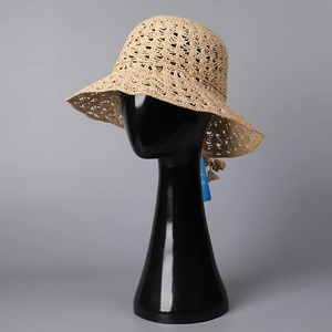 Vue détaillée du chapeau de paille crocheté avec motif ajouré et pompons