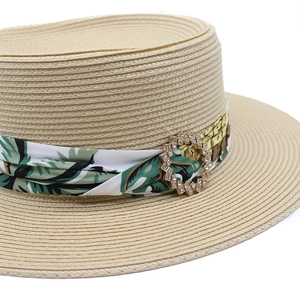 Détail d'un chapeau de paille beige avec ruban tropical et boucle en strass brillant