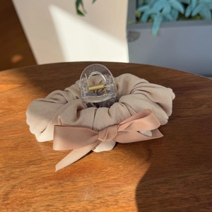 Close-up of cream bow scrunchie and transparent hair claw on a rustic wooden table