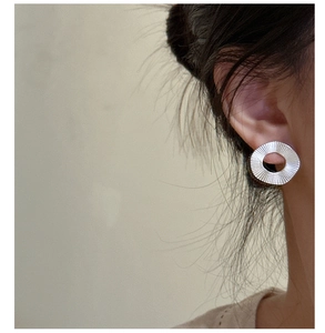 Détail macro d'une boucle d'oreille ronde en argent S925 à texture plissée