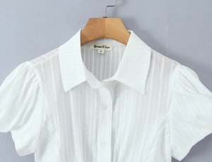 Detail of white puff sleeve polo shirt showing vertical texture and pointed collar