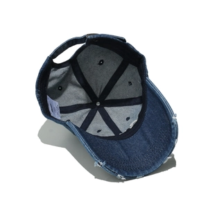 Close-up of distressed denim baseball cap detailing worn edges and metal buckle strap