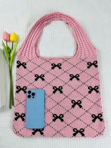 Detailed close-up of a pink knit tote bag with black bow patterns and waffle texture