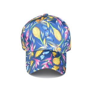 Detail view of the tropical floral and butterfly print on a navy blue satin baseball cap