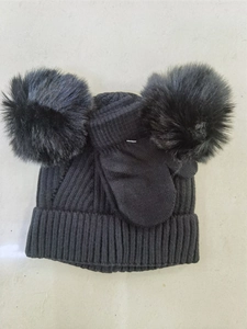 Detail of black knit winter hat and gloves set featuring dual faux fur pom-poms for kids