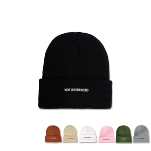Detail showing various colors and white NOT INTERESTED embroidery on the knit beanie